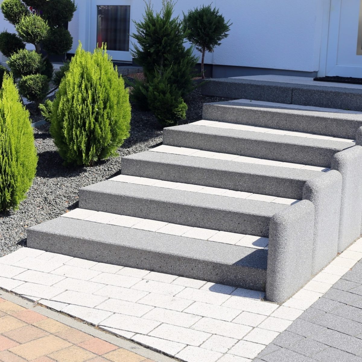 Neat and tidy front yard with solid block steps, decorative gravel and planting